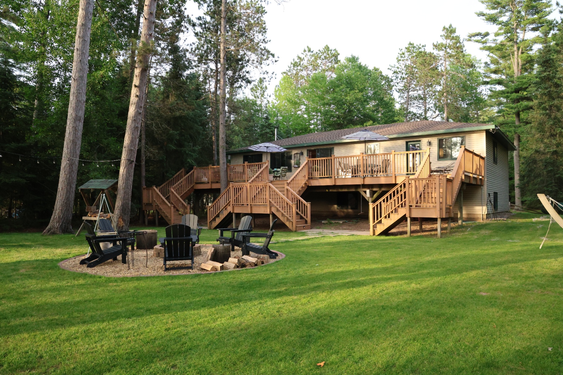 Lodge exterior from the lake with wraparound deck and fire pit