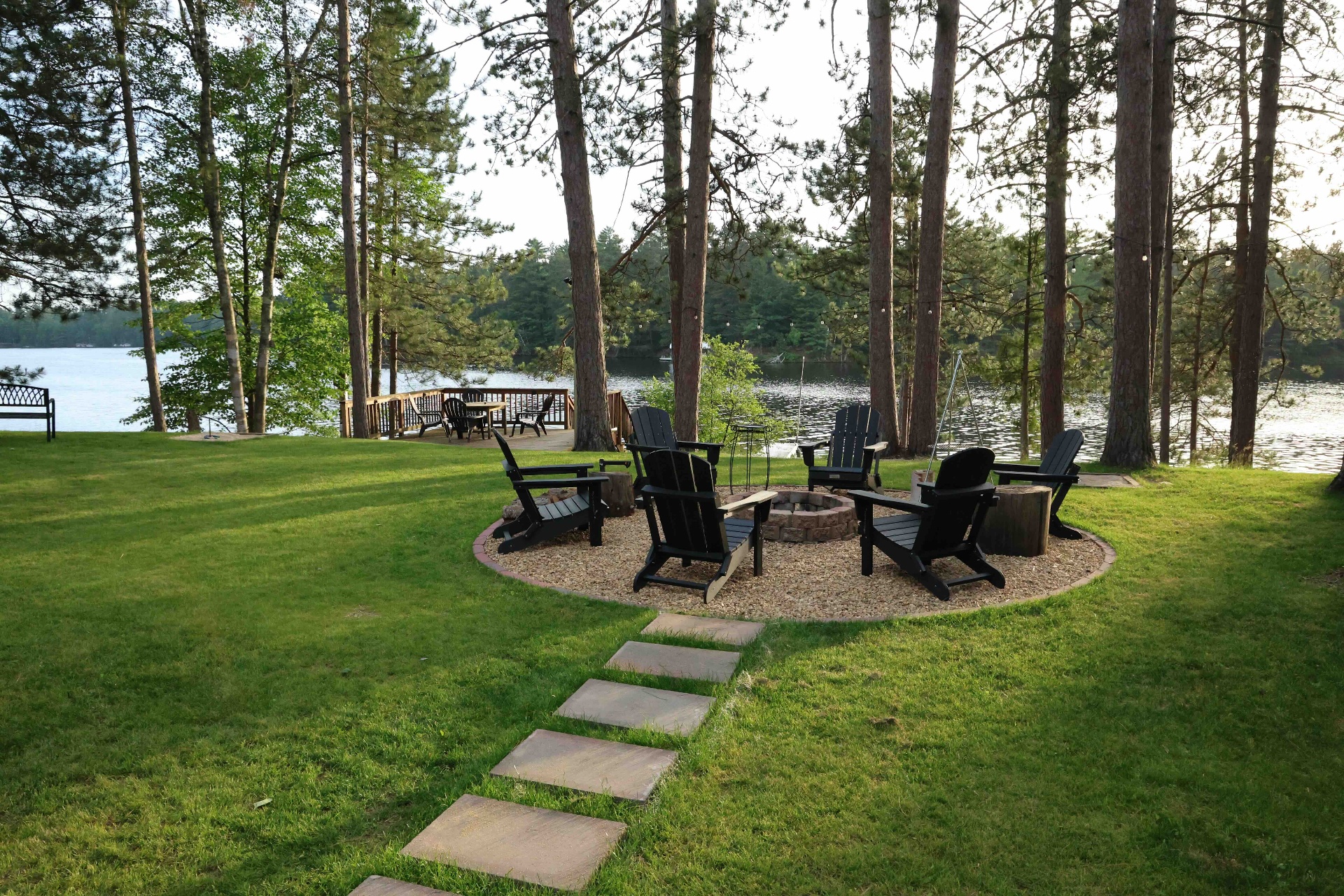 Fire pit circle with Adirondack chairs beside the lake